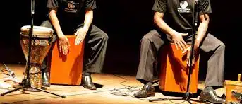Musiciens jouant des percussions cajons sur scène.