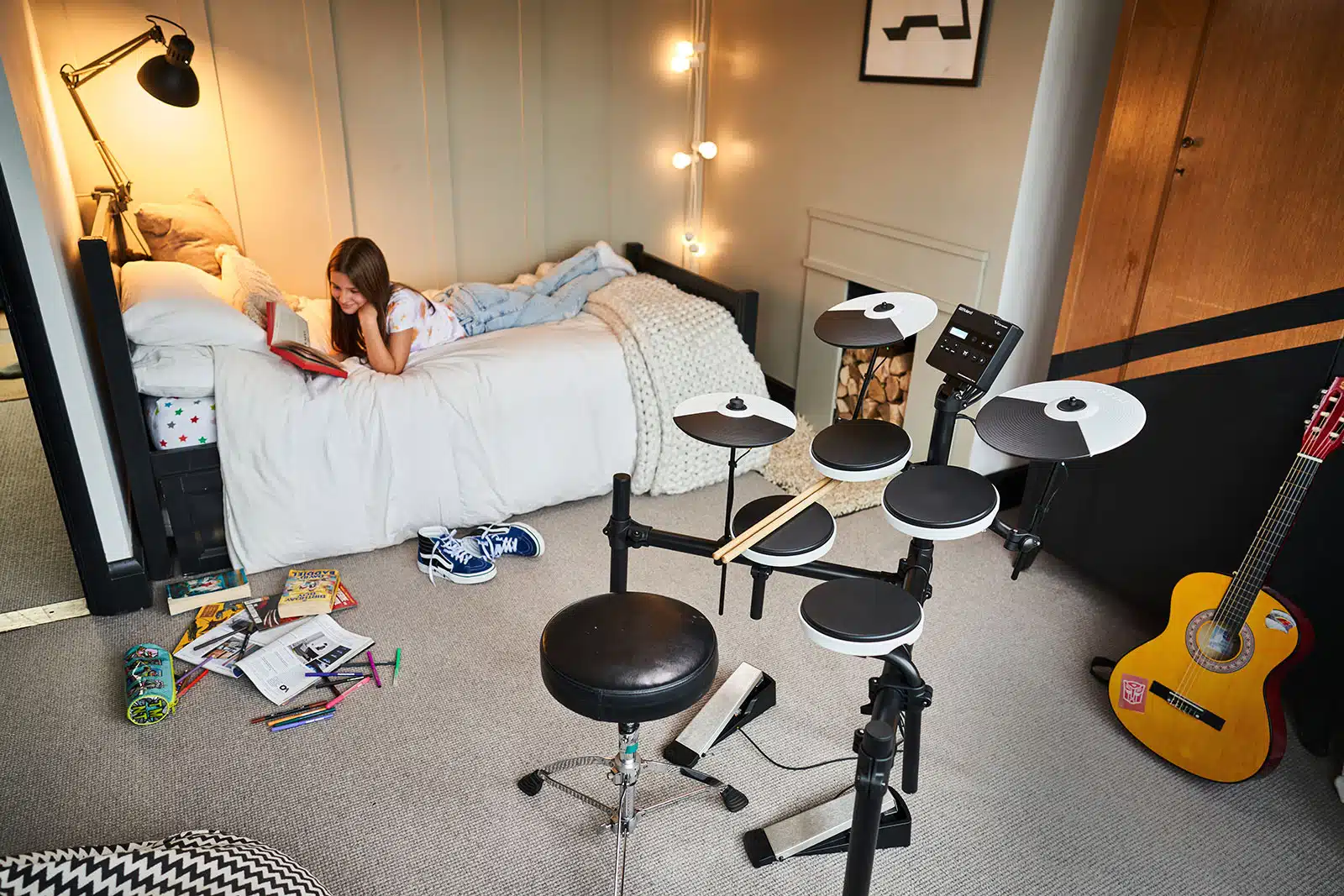 a girl lying on a bed with a drum set and a book Roland TD-02K leguidedesbatteurs.com