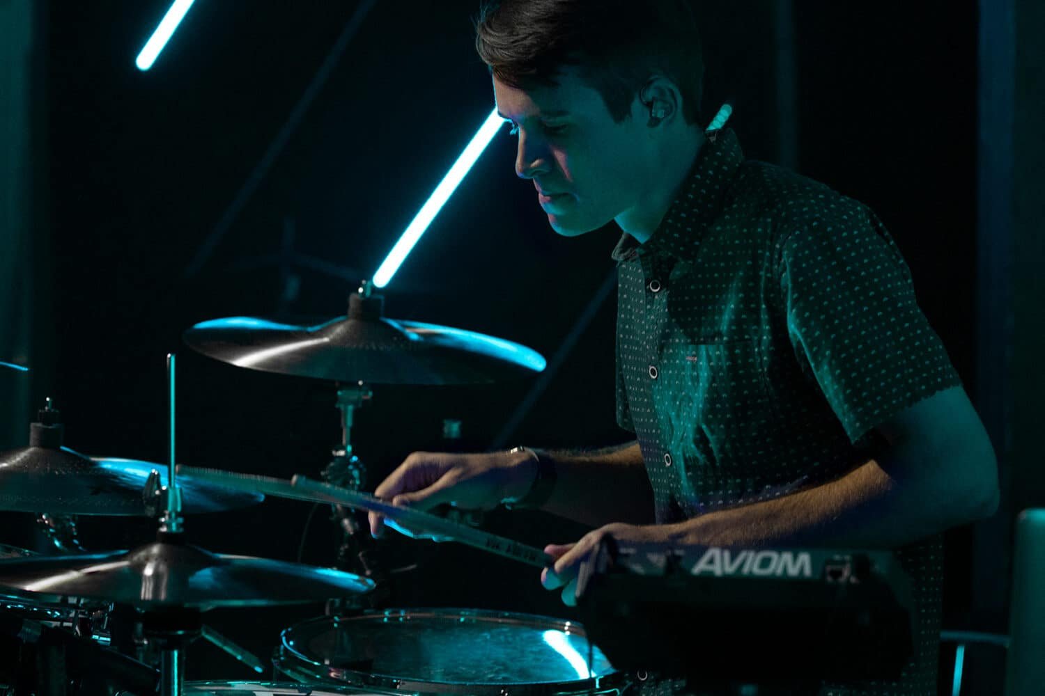 Batteur jouant sur scène sous des néons bleus, cymbales Sabian FRX au premier plan