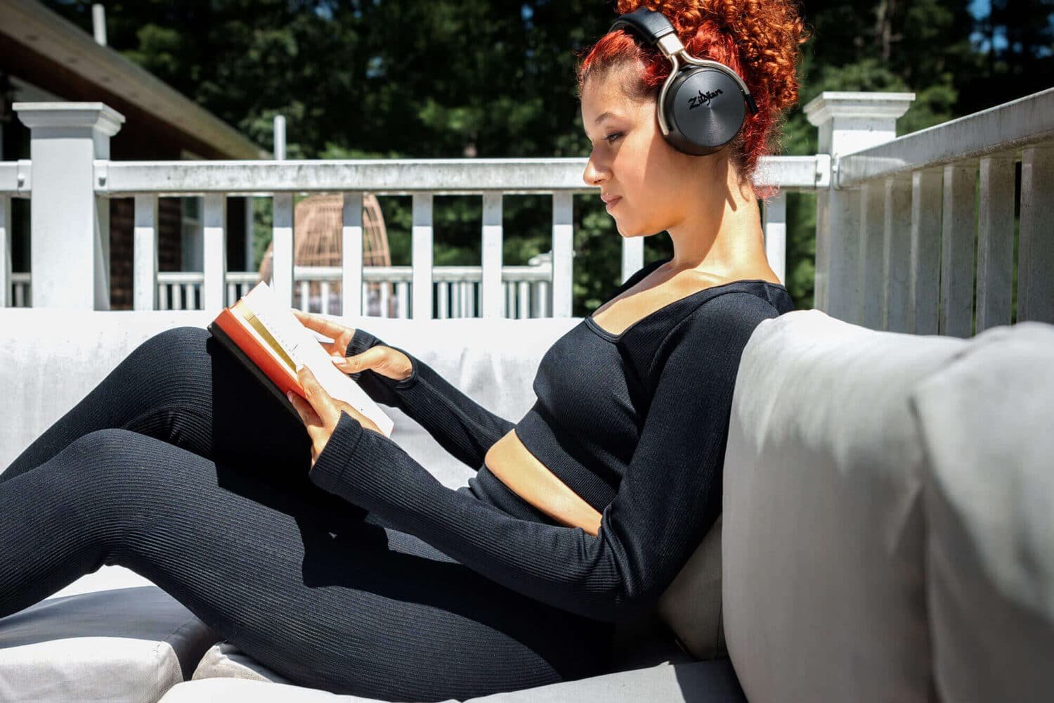 Jeune femme lisant sur une terrasse en portant le casque Zildjian ALCHEM-E noir