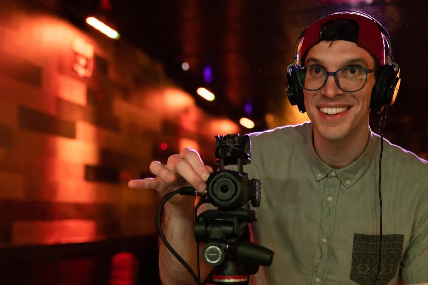 Vidéaste au casque réglant le Zoom Q8n-4K sur trépied dans une salle de concert