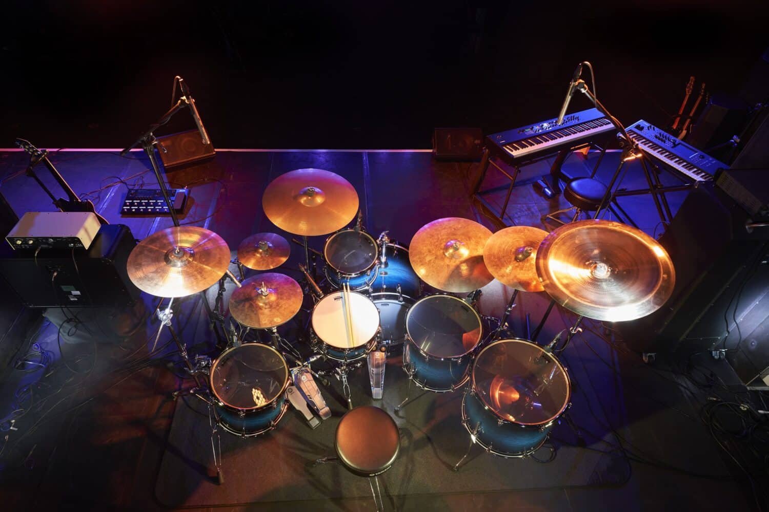 Batterie Yamaha Live Custom Hybrid Oak installée sur scène, vue plongeante avec micros, claviers et amplis