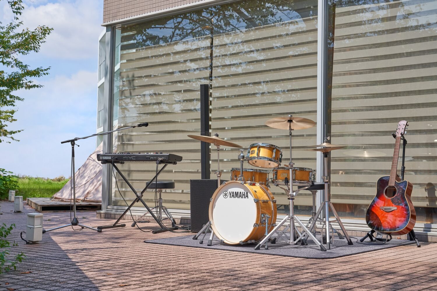 Batterie Yamaha Stage Custom Hip installée en extérieur sur une terrasse avec clavier, micro et guitare